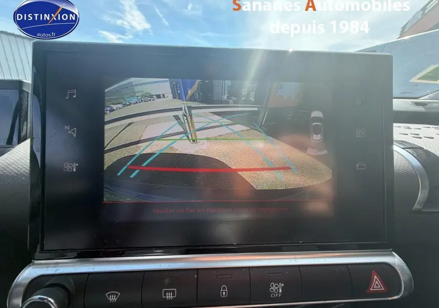 Écran tactile intérieur montrant la caméra de recul d'une Citroën C4 Cactus bleu métal, vue depuis le tableau de bord.