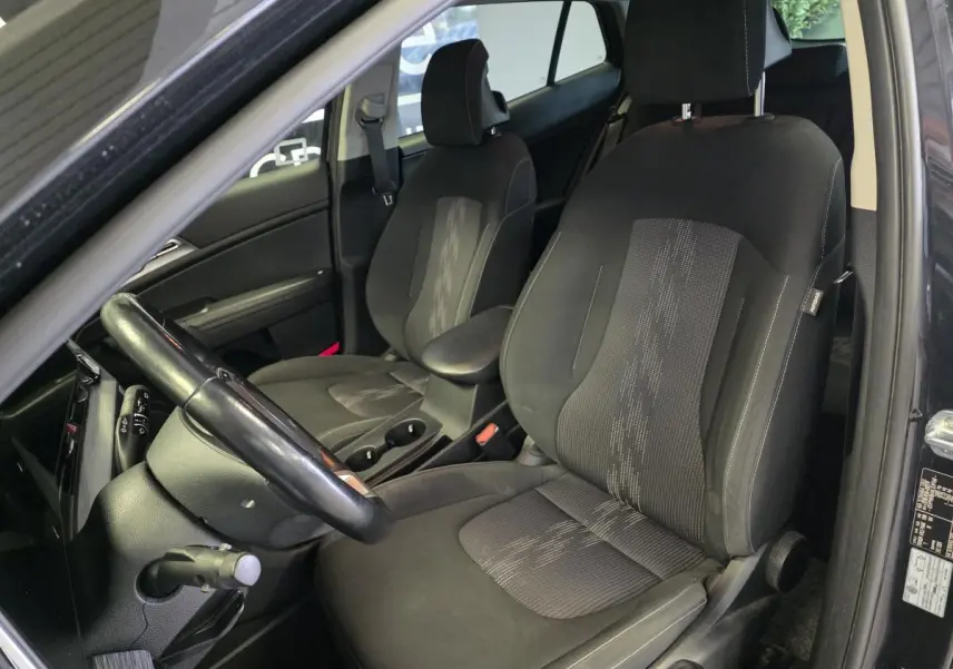 Intérieur noir du Kia Sportage 2022, vue côté conducteur montrant sièges tissu et volant cuir.