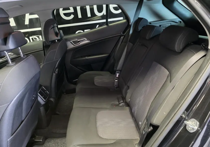 Vue intérieure côté droit sur la banquette arrière noire en tissu du Kia Sportage 2022 avec appuie-têtes et ceintures visibles.