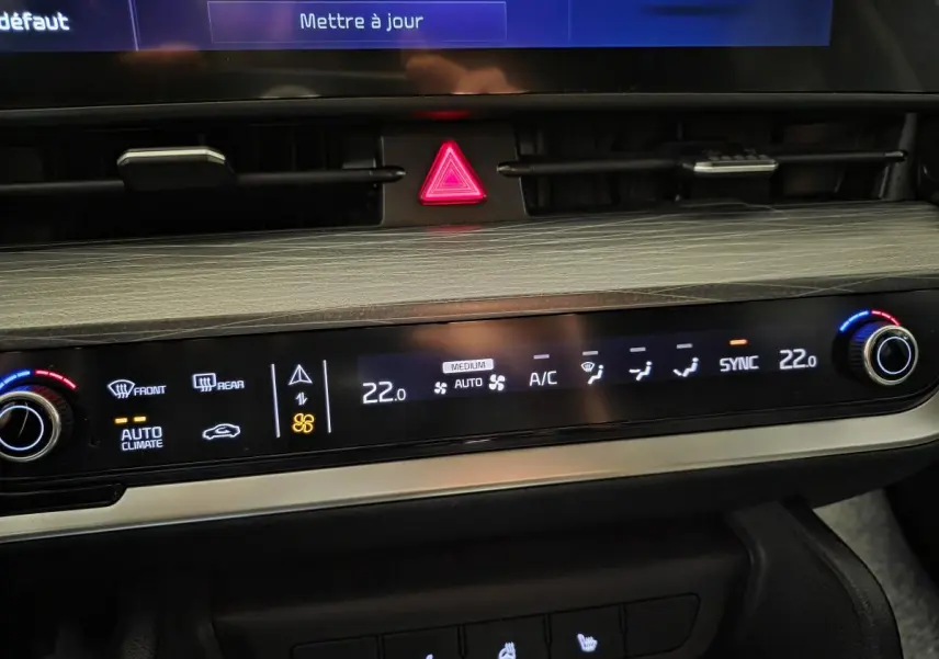 Vue rapprochée de la console centrale du Kia Sportage noir 2022, affichant la climatisation automatique et les commandes tactiles.