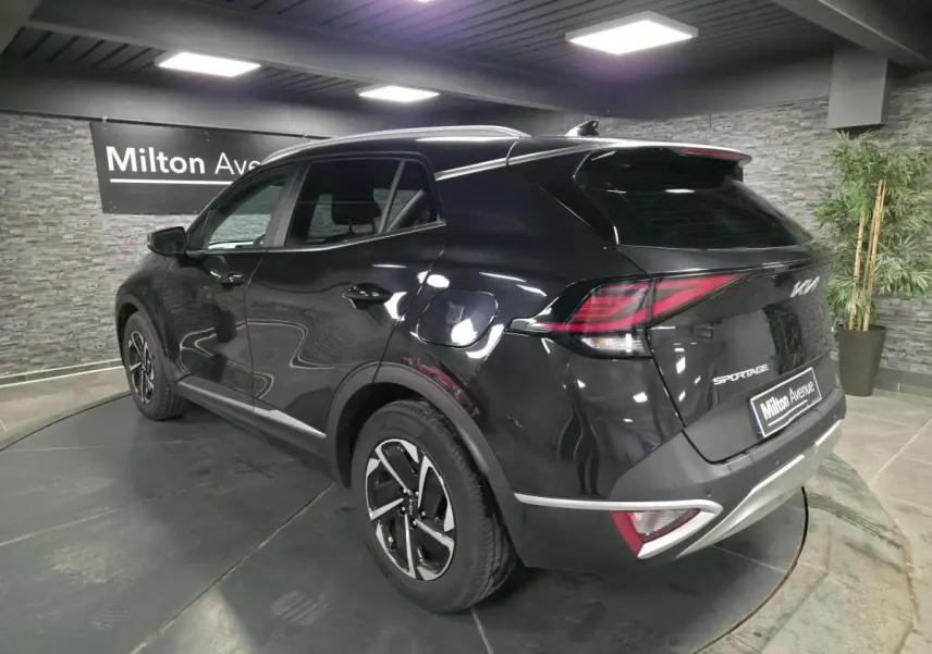 Vue 3/4 arrière droite du KIA SPORTAGE noir avec feux arrière LED et jantes alliage 17 pouces en showroom.