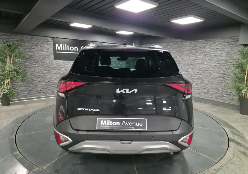 Vue arrière d'un Kia Sportage noir 2022 avec feux arrière LED et bouclier argenté en showroom.