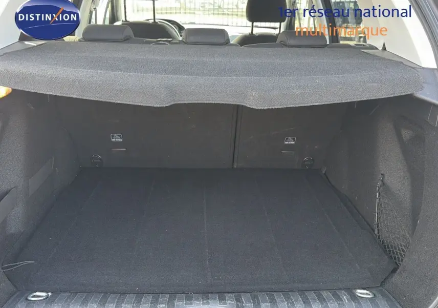 Coffre ouvert d'un Peugeot 2008 gris platinium, vue arrière montrant le tapis de coffre et la plage arrière.