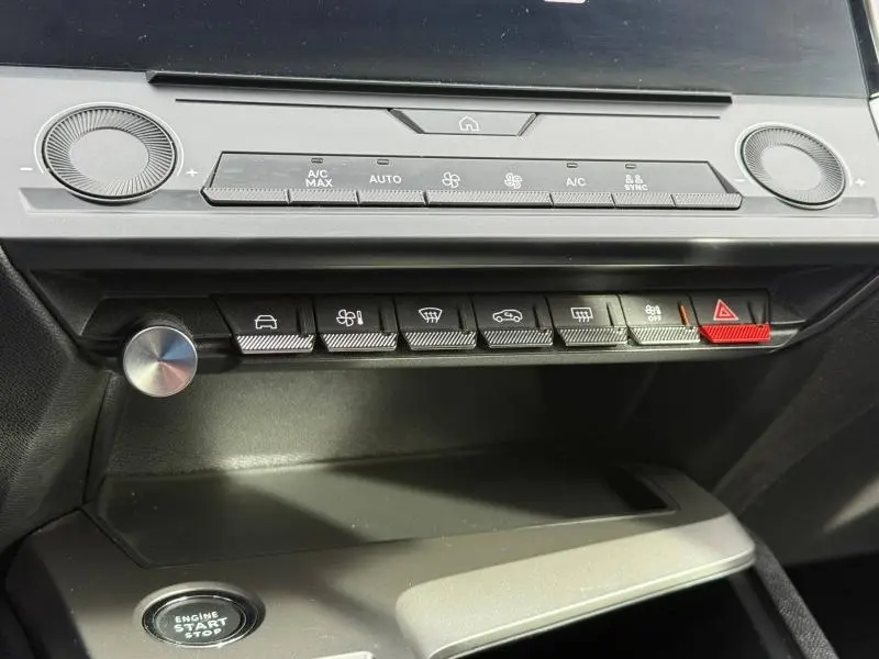 Vue rapprochée de la console centrale de la Peugeot 308 2024 noire, montrant les commandes climatisation et boutons fonctionnels.