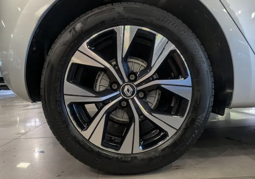 Gros plan sur la roue avant droite de la Renault Clio V gris platine, avec jante alliage bicolore et logo Renault central.