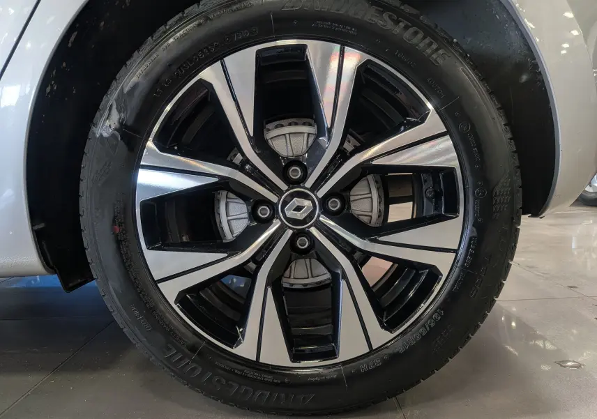 Gros plan sur la jante alliage bicolore noir et argent d'une Renault Clio V gris platine, roue avant droite visible.