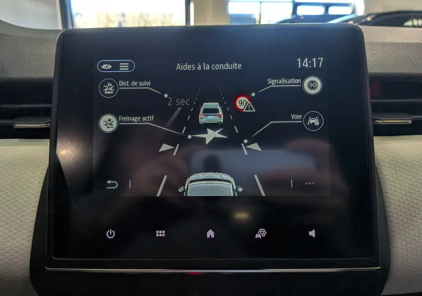 Écran tactile intérieur de la Renault Clio V gris platine montrant les aides à la conduite avec suivi de distance et freinage actif.