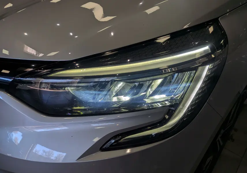 Gros plan sur le phare avant droit de la Renault Clio V gris platine, mettant en valeur son design LED moderne.
