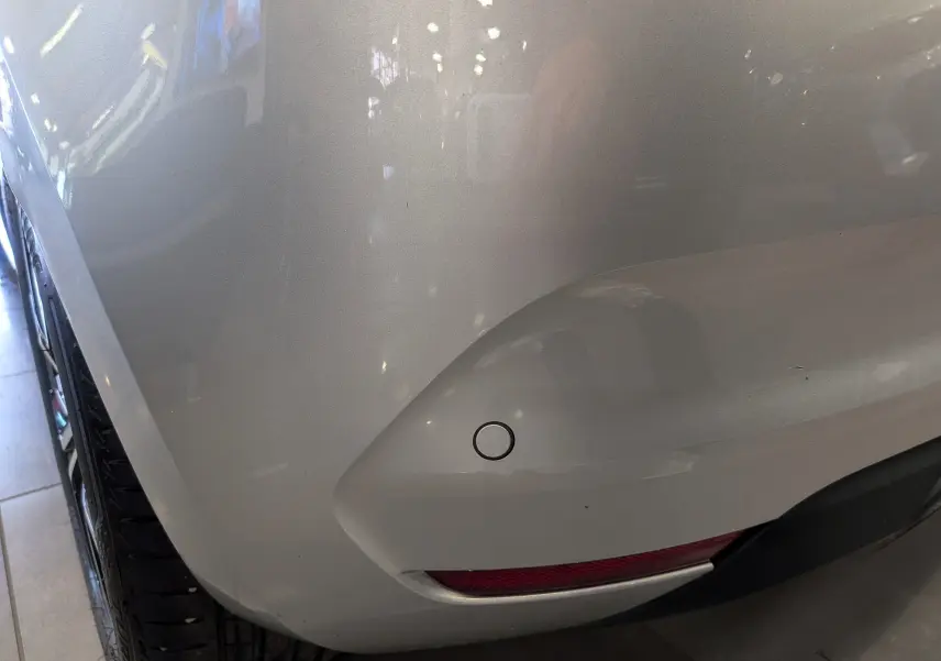 Gros plan sur l'angle arrière droit d'une Renault Clio V gris platine, avec capteur de recul et feu antibrouillard visible.