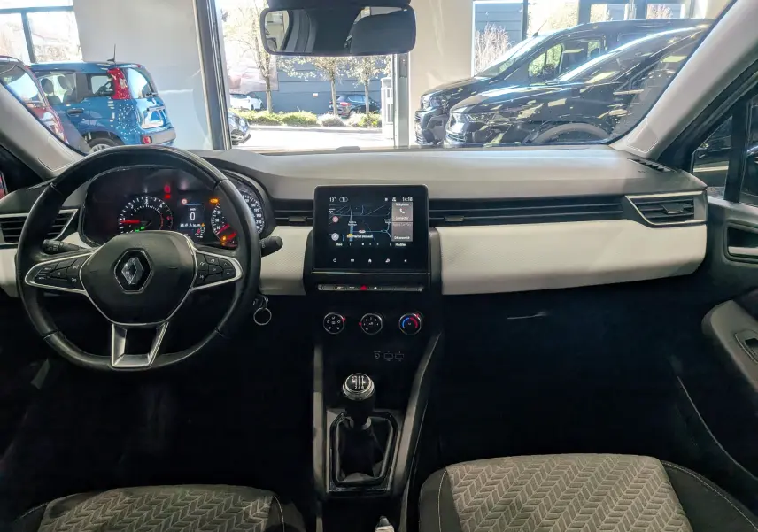 Vue intérieure avant de la Renault Clio V gris platine, tableau de bord avec écran tactile et volant multifonction.
