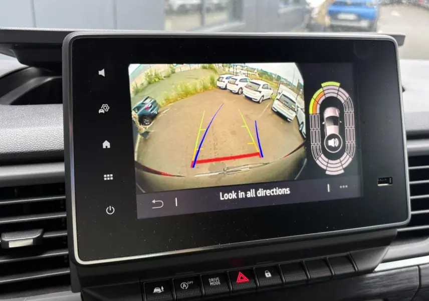 Écran tactile intérieur montrant la caméra de recul du Nissan Primastar gris Comète, avec guidage de trajectoire coloré.