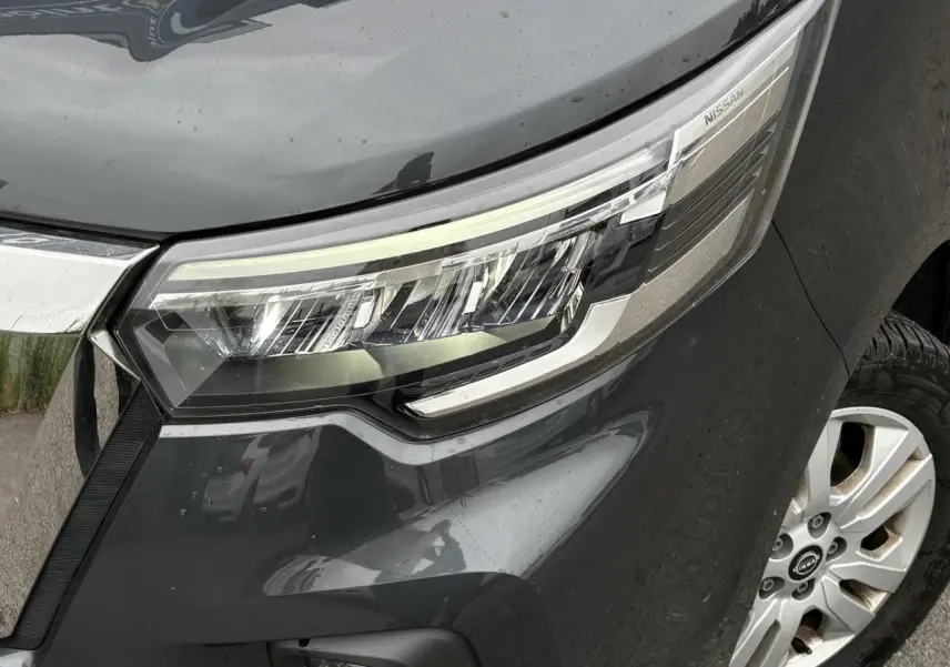 Gros plan sur le phare avant droit gris comète du Nissan Primastar 2025 avec jante alliage visible.