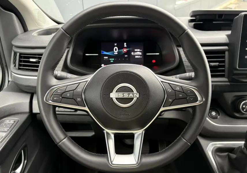 Vue rapprochée du volant noir du Nissan Primastar 2025 avec commandes intégrées et tableau de bord numérique.
