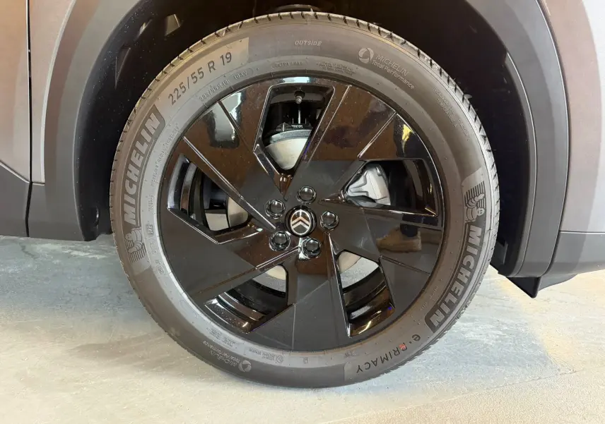 Gros plan sur la roue avant droite du Citroën C5 Aircross gris, jante noire brillante avec logo Citroën central.