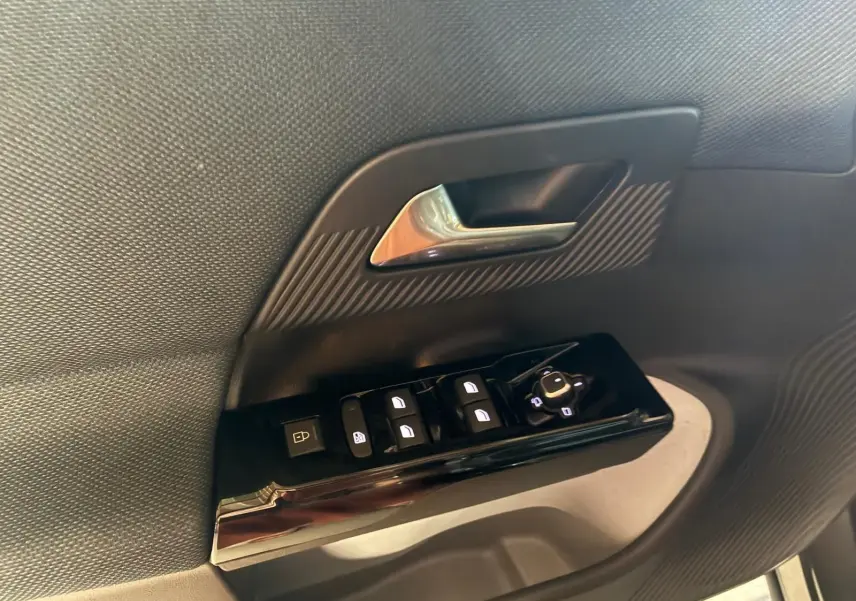 Gros plan sur la commande des vitres et la poignée intérieure côté conducteur d’un Citroën C5 Aircross gris, finition 2026.