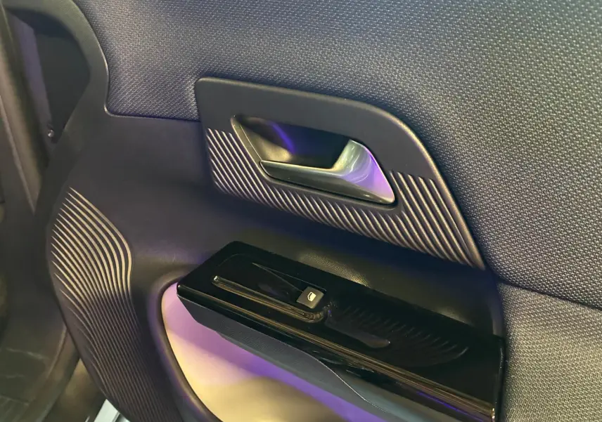 Détail de la porte intérieure côté droit du Citroën C5 Aircross gris, avec poignée argentée et commande de fenêtre noire.
