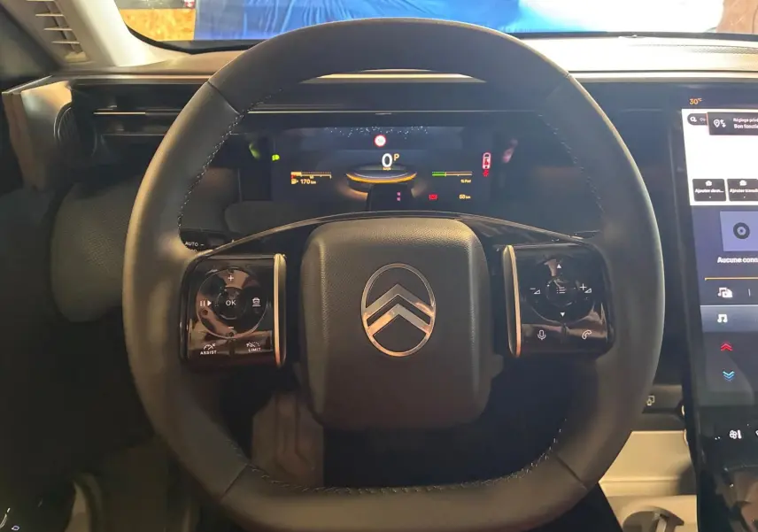 Vue rapprochée du volant noir du Citroën C5 Aircross 1.2 Hybride 2026 avec tableau de bord numérique et écran tactile.