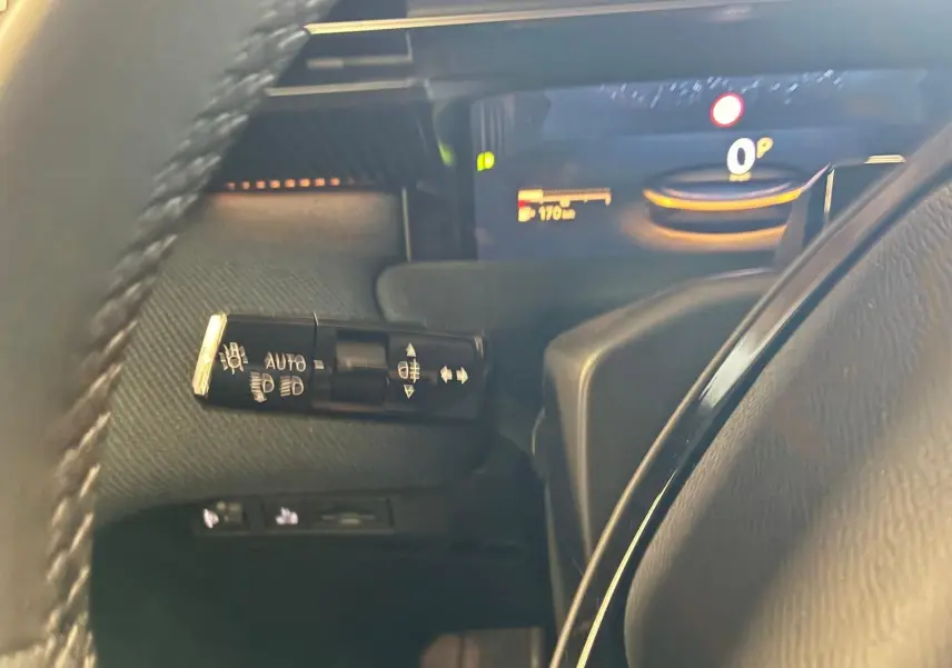 Gros plan sur la commande des phares à gauche du volant dans l’habitacle noir du Citroën C5 Aircross gris 2026.