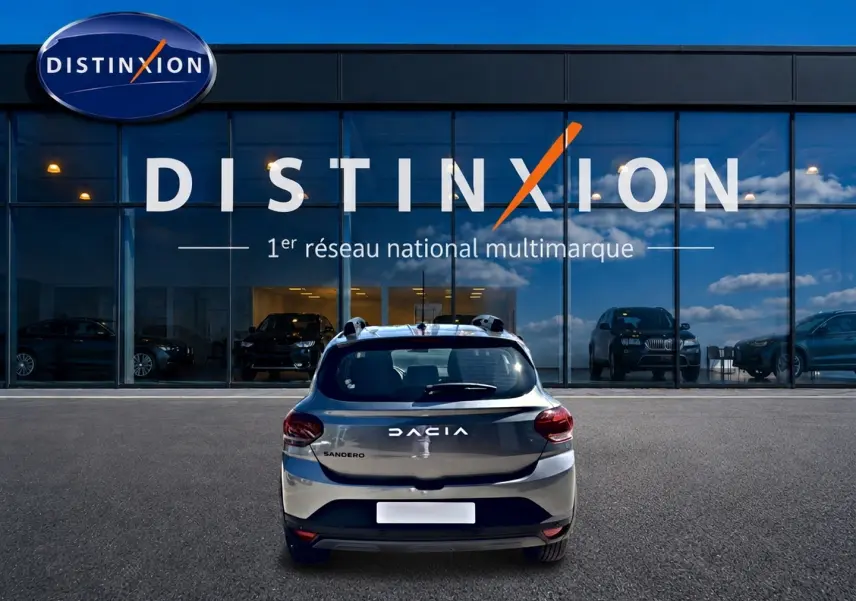 Vue arrière d'une Dacia Sandero gris schiste garée devant une vitrine avec logo Distinxion.