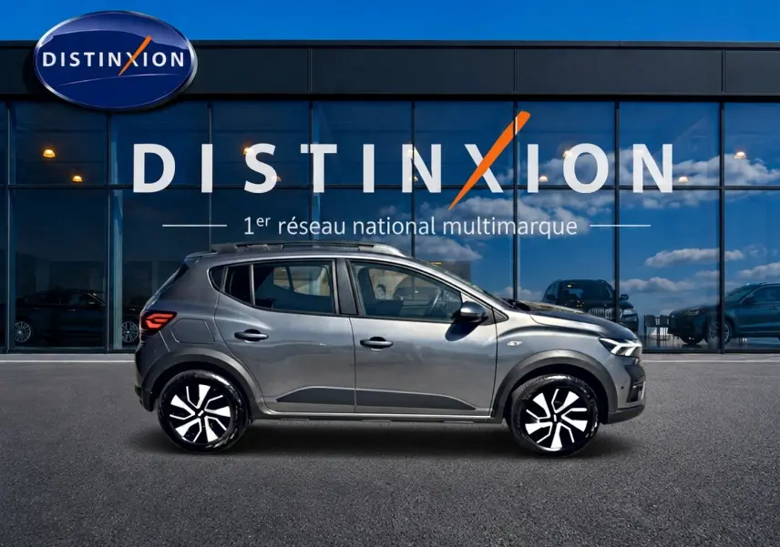 Vue de profil côté gauche d'une Dacia Sandero Stepway 2025 gris schiste avec barres de toit et jantes distinctives.