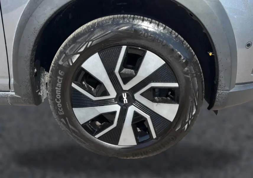 Gros plan sur la roue avant droite du Dacia Sandero gris schiste, avec jante au design moderne bicolore.