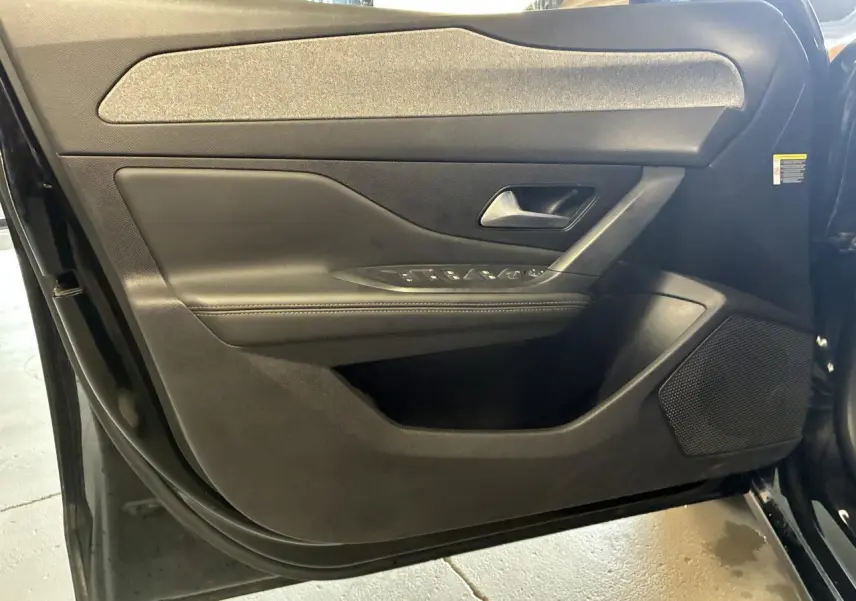 Vue intérieure de la porte avant gauche noire de la Peugeot 308 SW 2024 avec commandes de vitres et haut-parleur intégré.
