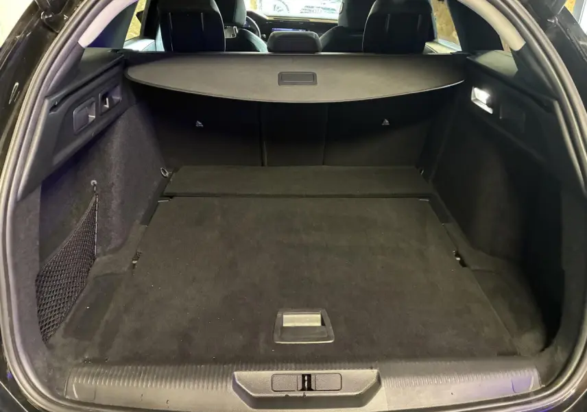 Coffre ouvert de la Peugeot 308 SW noire, vue arrière montrant l’espace de chargement et la plage arrière.