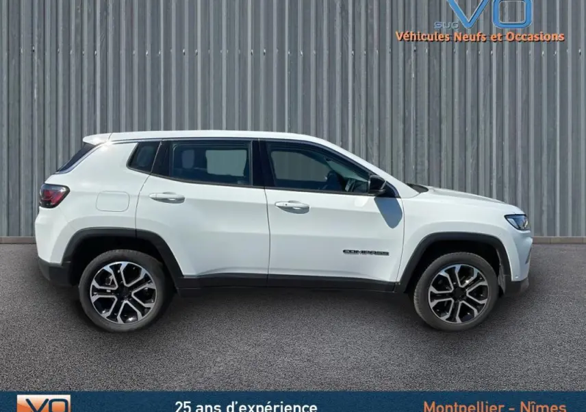 Profil côté gauche d'un Jeep Compass blanc 2024 avec jantes alliage 18 pouces sur fond urbain.