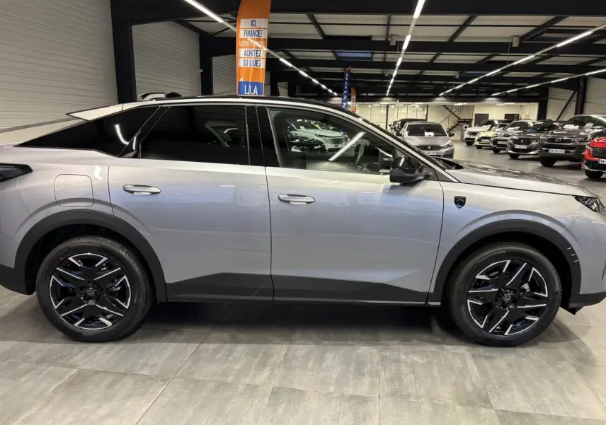 Vue de profil côté gauche d’un Peugeot 3008 gris Artense avec jantes alliage noires et toit noir en showroom.