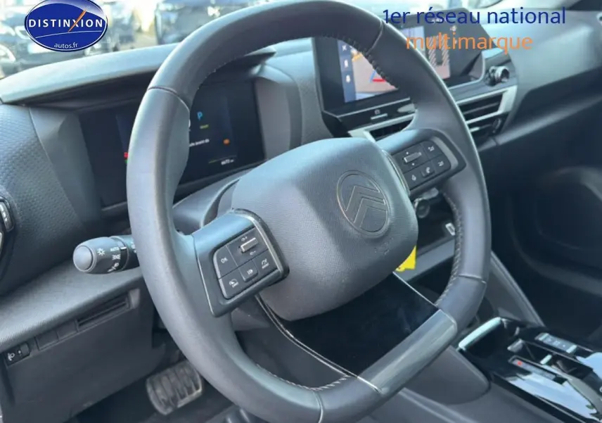Vue intérieure centrée sur le volant multifonctions de la Citroën C4 électrique 2025, avec tableau de bord numérique.