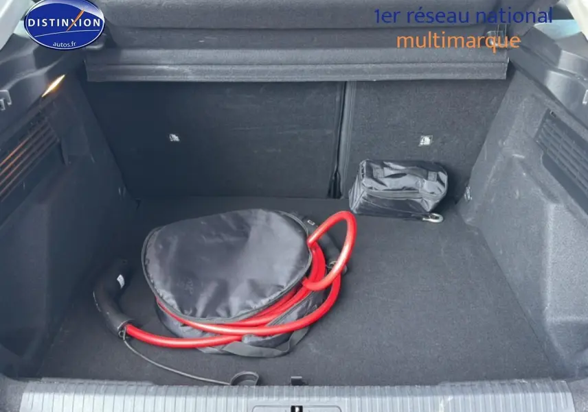 Coffre ouvert vu de face d'une Citroën C4 électrique gris foncé avec câble de recharge rouge rangé à l'intérieur.