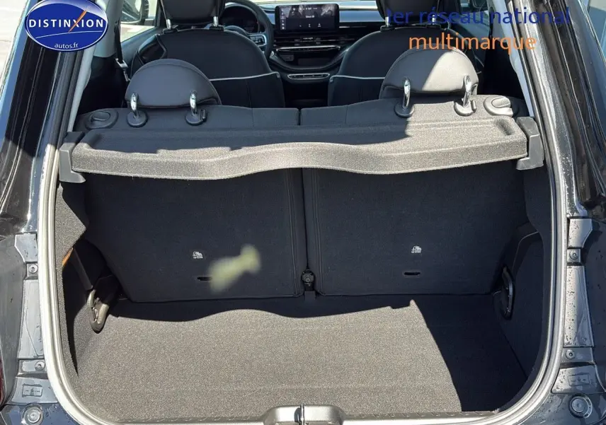 Coffre ouvert vu de l'arrière d'une Fiat 500 électrique blanche 2024 avec banquette arrière et tablette cache-bagages.