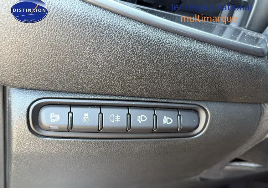 Boutons de commande des aides à la conduite sur tableau de bord noir de Fiat 500 électrique blanc, vue rapprochée côté gauche.