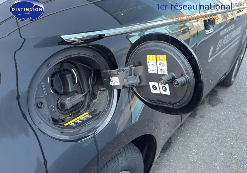 Détail de la trappe de recharge ouverte côté gauche d’une Fiat 500 électrique blanche, vue rapprochée.