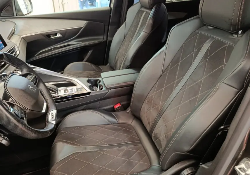 Vue intérieure côté conducteur du Peugeot 5008 gris clair, avec sièges en cuir et alcantara, volant multifonctions.