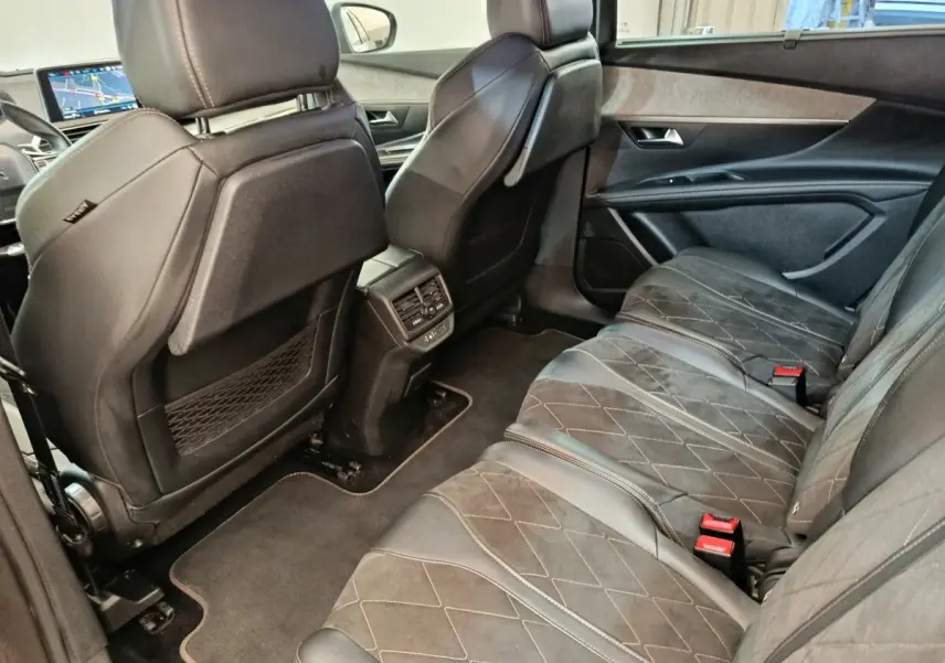 Vue intérieure arrière côté droit du Peugeot 5008 gris clair, montrant les sièges en cuir et alcantara avec coutures apparentes.