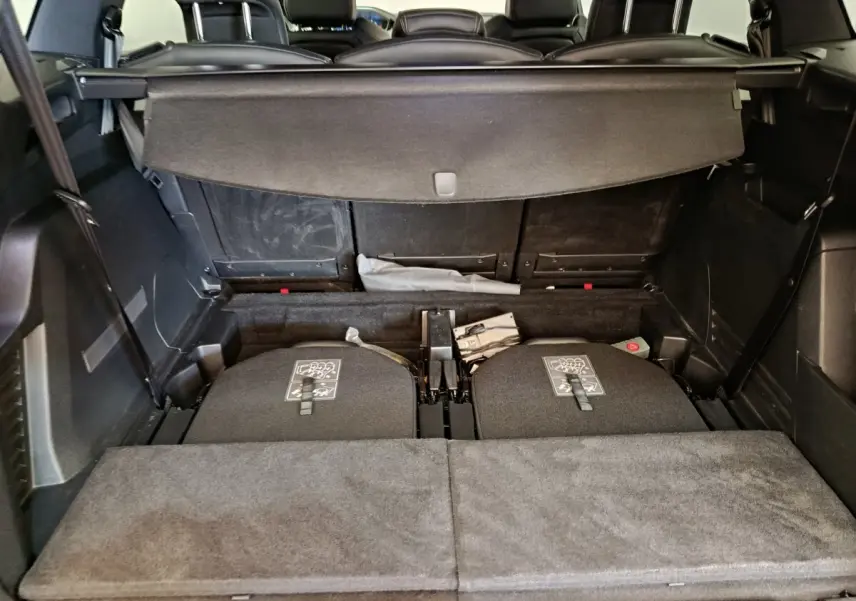 Vue du coffre arrière du Peugeot 5008 gris clair, montrant les sièges arrière rabattus et la tablette cache-bagages déployée.