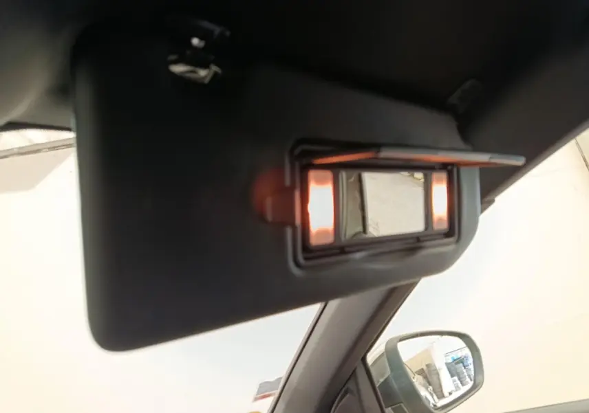 Miroir de courtoisie éclairé sur pare-soleil côté conducteur dans Peugeot 5008 gris clair, vue intérieure rapprochée.