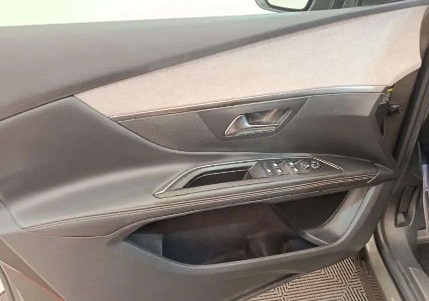 Vue rapprochée de la porte avant gauche du Peugeot 5008 gris clair, avec commandes électriques et garniture tissu et cuir.