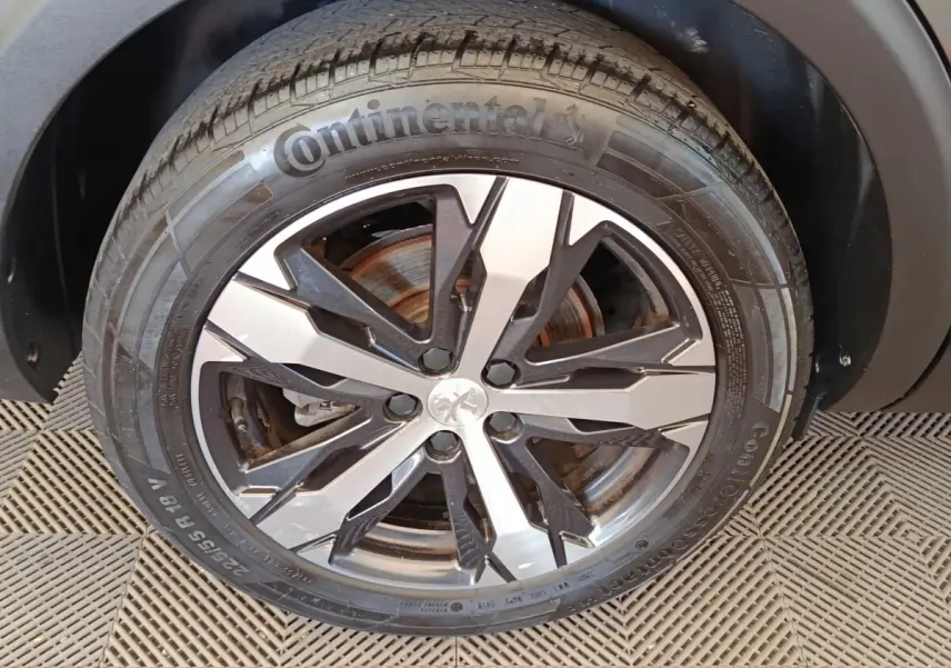 Gros plan sur la roue avant droite du Peugeot 5008 gris clair, mettant en valeur la jante alliage bicolore et le pneu Continental.