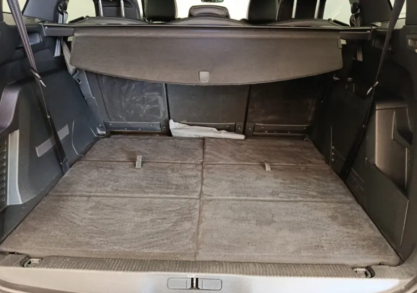 Vue du coffre arrière du Peugeot 5008 gris clair avec banquette rabattue et cache-bagages déployé.