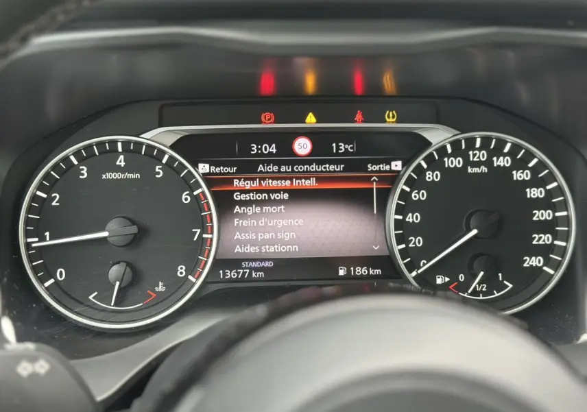 Vue rapprochée du tableau de bord du Nissan Qashqai 2025, affichant les compteurs et l'écran d'aide au conducteur.