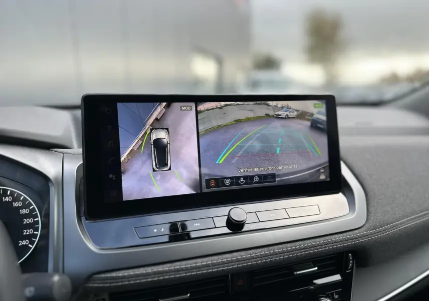 Vue intérieure du tableau de bord du Nissan Qashqai 2025, écran tactile affichant la caméra de recul et vue à 360° en noir nacré.