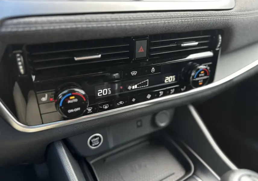Gros plan sur la console centrale du Nissan Qashqai 2025, affichant la climatisation automatique bi-zone et le bouton Start/Stop.