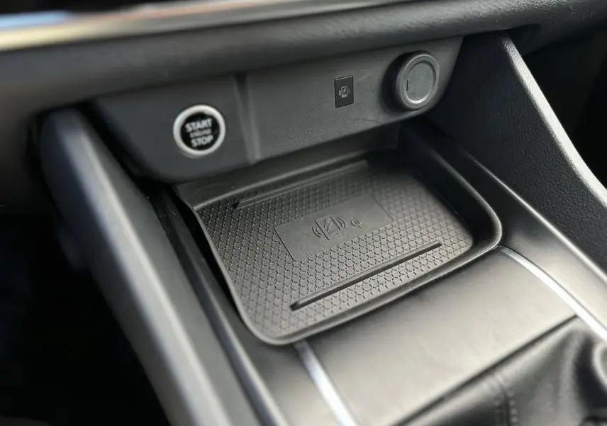 Gros plan sur la console centrale du Nissan Qashqai 2025 avec zone de recharge sans fil et bouton Start/Stop.