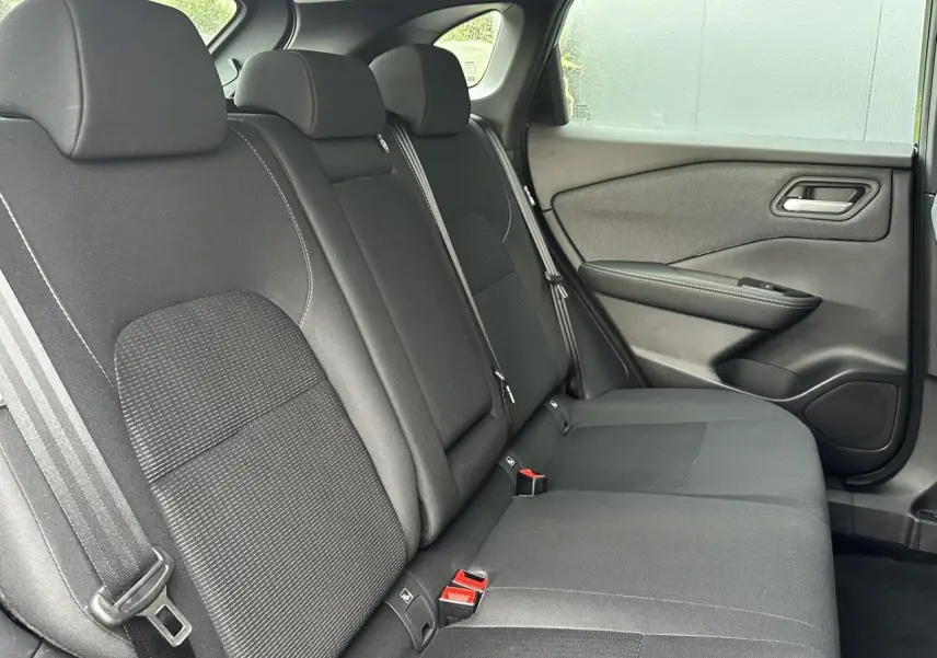 Vue latérale droite de la banquette arrière noire du Nissan Qashqai 2025, avec ceintures et garnitures de porte visibles.