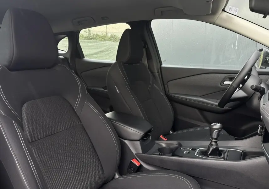 Vue intérieure côté droit du Nissan Qashqai 2025 noir nacré, sièges et console centrale avec boîte manuelle.