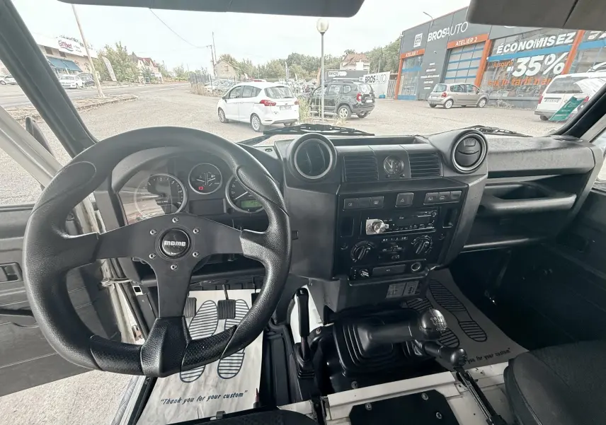Vue intérieure du Land Rover Defender 2.4 TD4 2007, montrant le volant Momo, tableau de bord noir et levier de vitesses manuel.