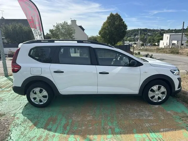 Vue de profil côté gauche d'un Renault Dacia Jogger blanc 2023, break compact avec toit noir et jantes acier.