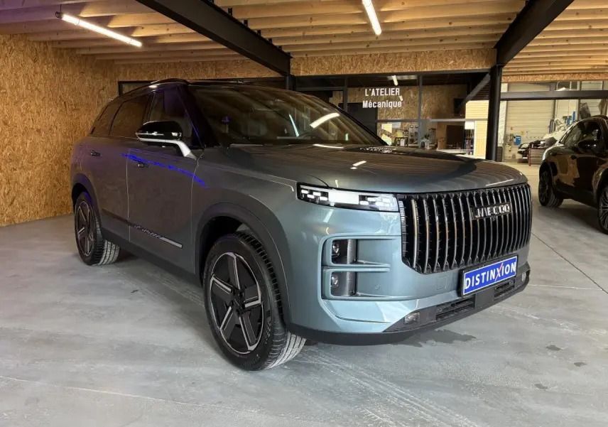 SUV JAECOO J7 gris olive en 3/4 avant droit, avec calandre verticale noire et jantes alliage modernes.